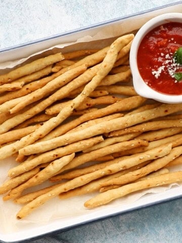 long thin breadsticks in a white tray.