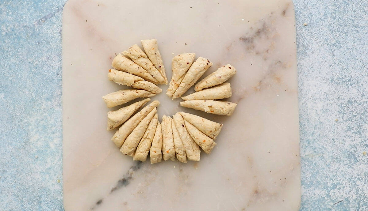 cut triangle pieces of breadstick dough placed on a white marble.