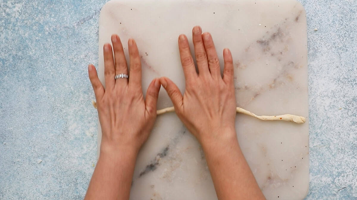 two hands rolling one lone breadstick.