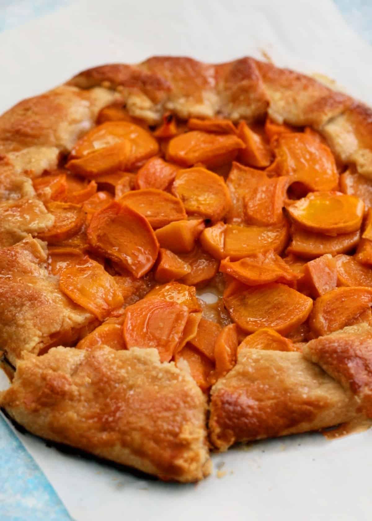one round persimmon galette on a white parchment paper.