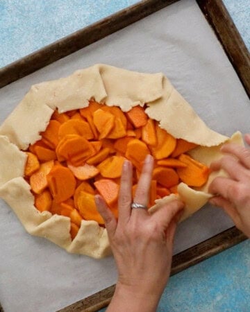 two hands folding the outer edge of a galette.