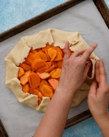 two hands folding the outer edge of a galette.