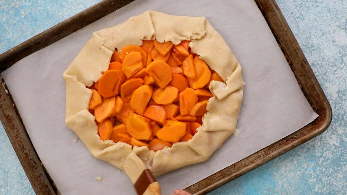 one unbaked persimmon galette placed on a parchment lined baking sheet.