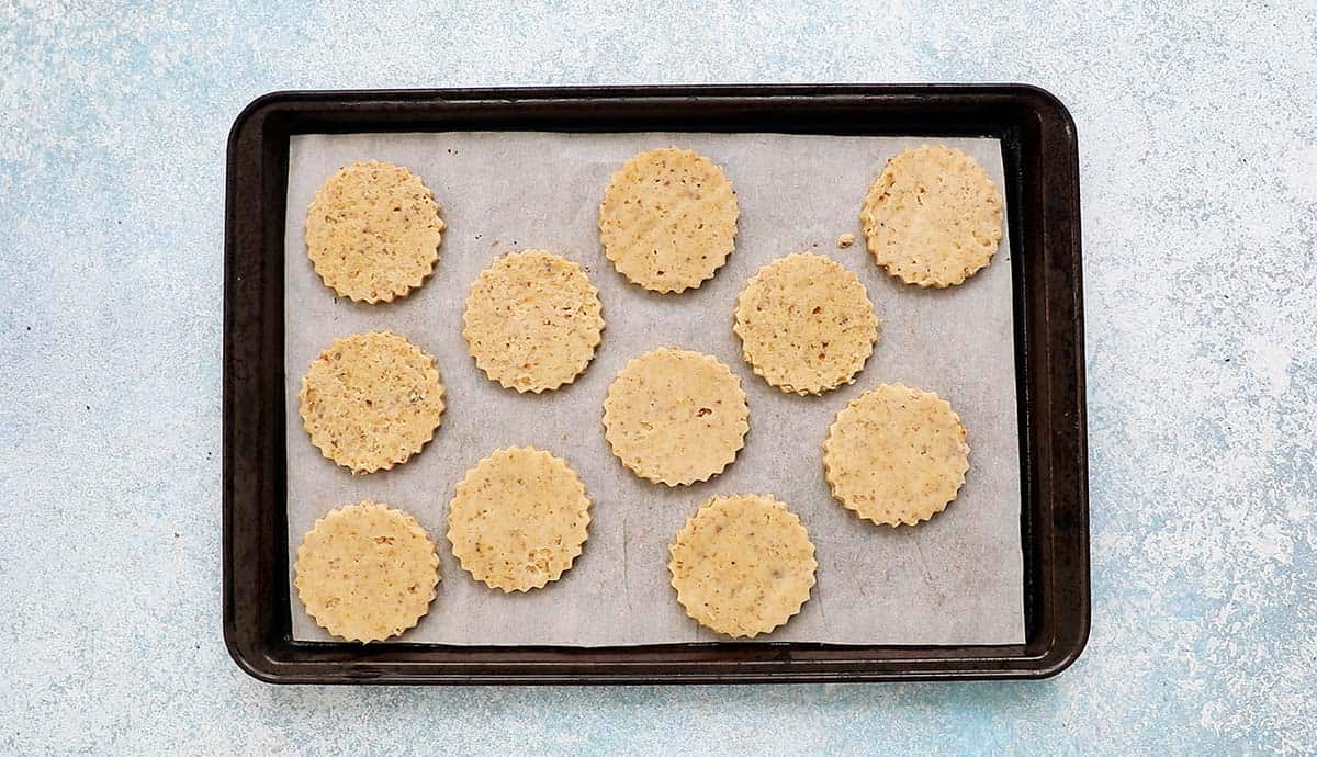 cut cookie dough circles placed on a parchment lined metal baking sheet.
