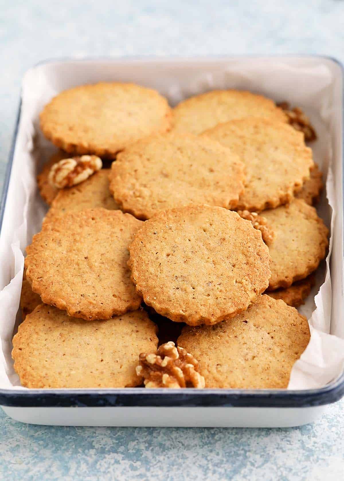 round shaped walnut cookies placed on a white rectangular tray.