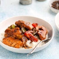 black pepper chicken stir fry over white rice in a round white bowl.