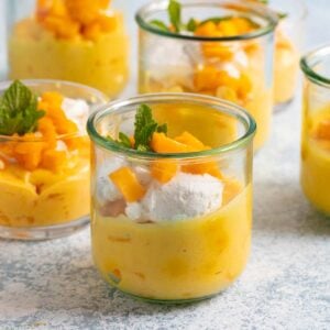 mango mousse in glass jars with whipped cream and mint.
