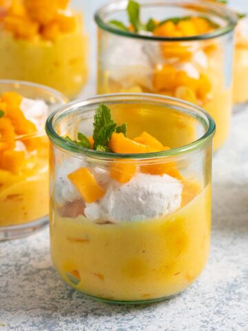 mango mousse in glass jars with whipped cream and mint.