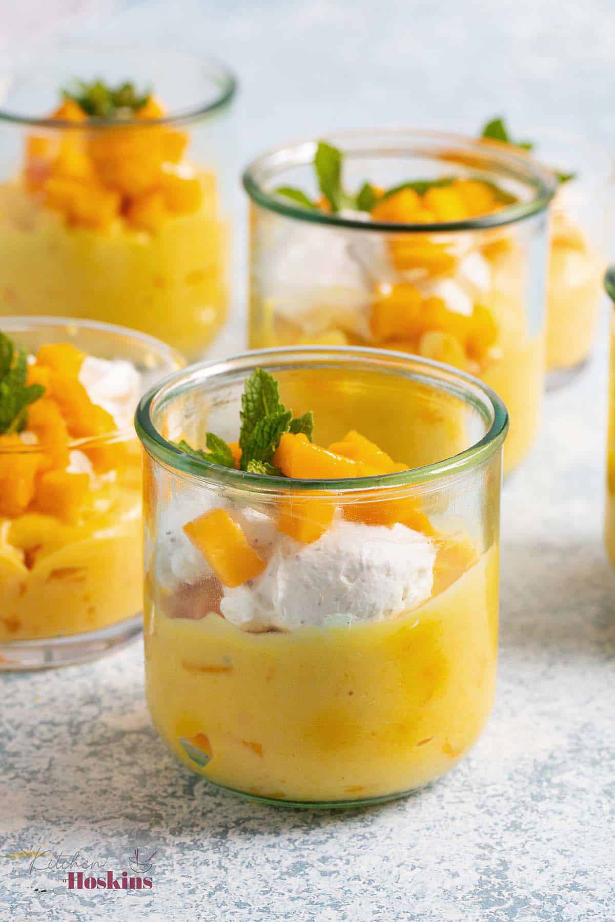 4 glass cups with yellow mousse and topped with white cream.