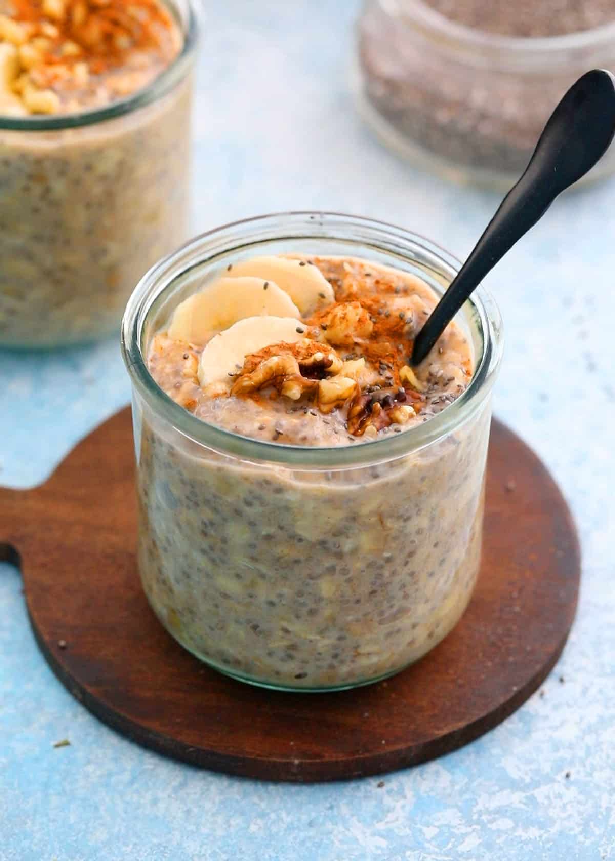 one glass jar with overnight oats topped with banana slices and walnut.