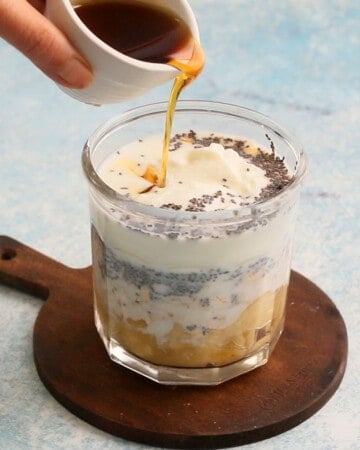 a hand pouring maple syrup into a glass jar.