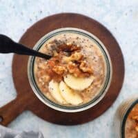 one glass jar with overnight oats topped with banana slices and walnut.