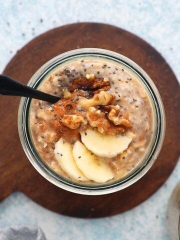 one glass jar with overnight oats topped with banana slices and walnut.