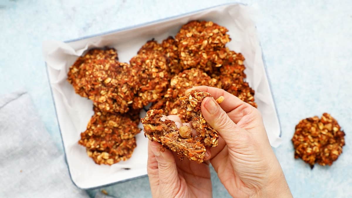 two hands breaking apart a carrot cookie.