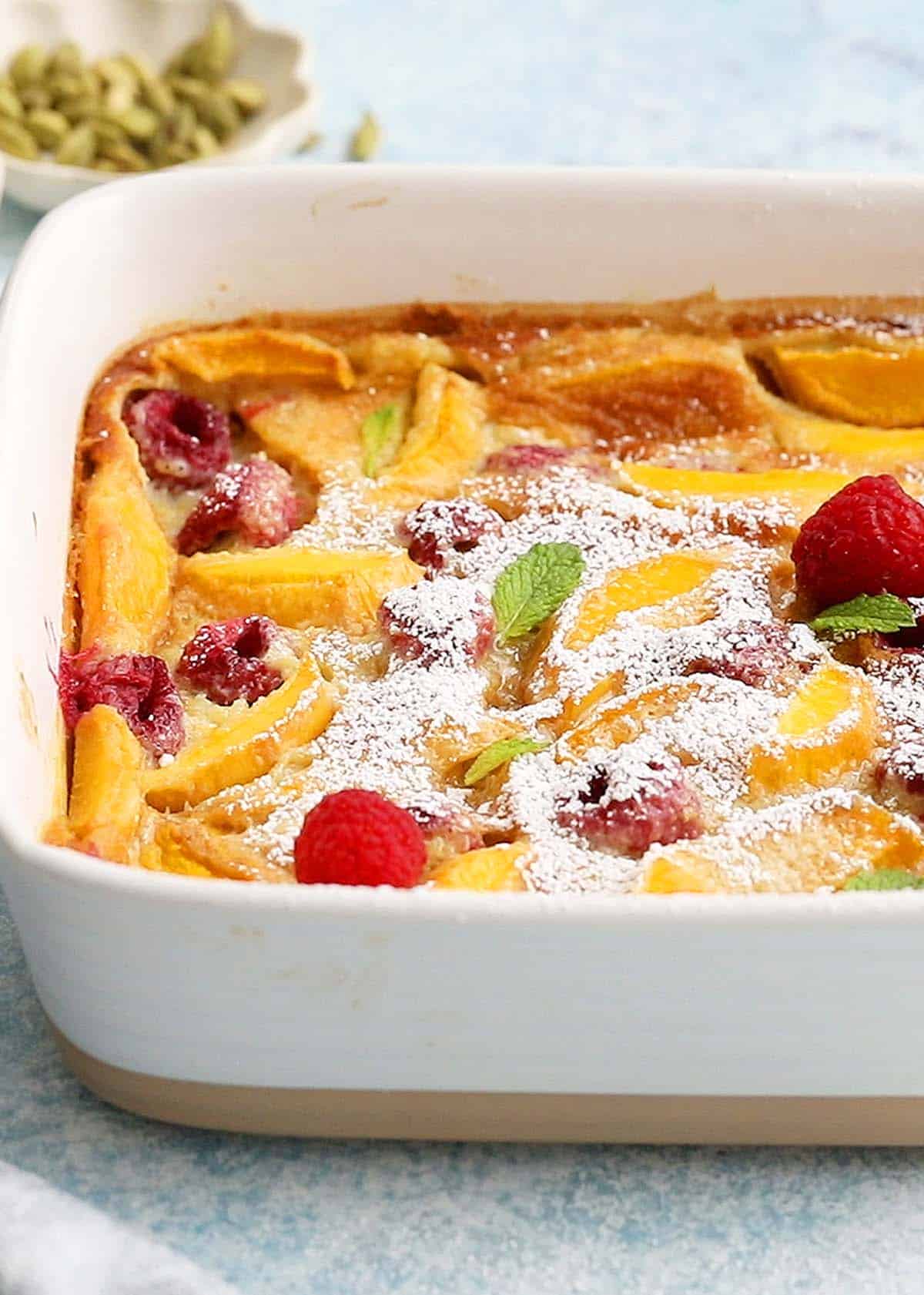 baked yellow clafoutis in a white baking dish.