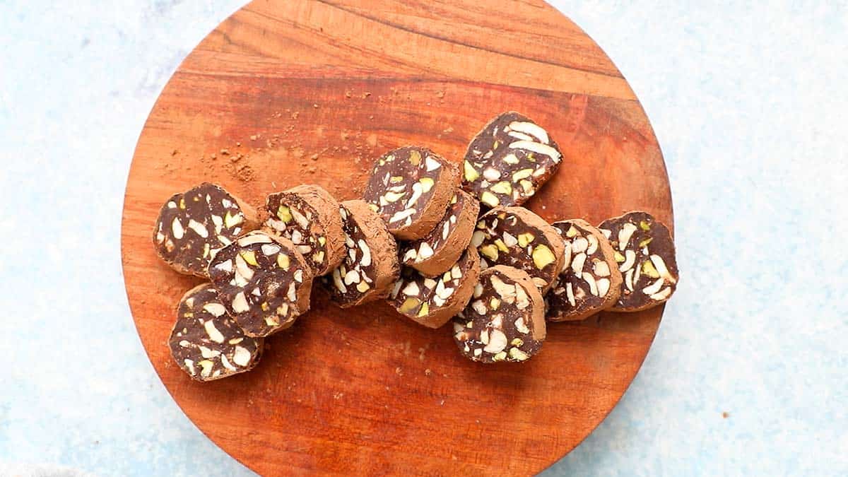 sliced chocolate salami placed on a round wooden board.