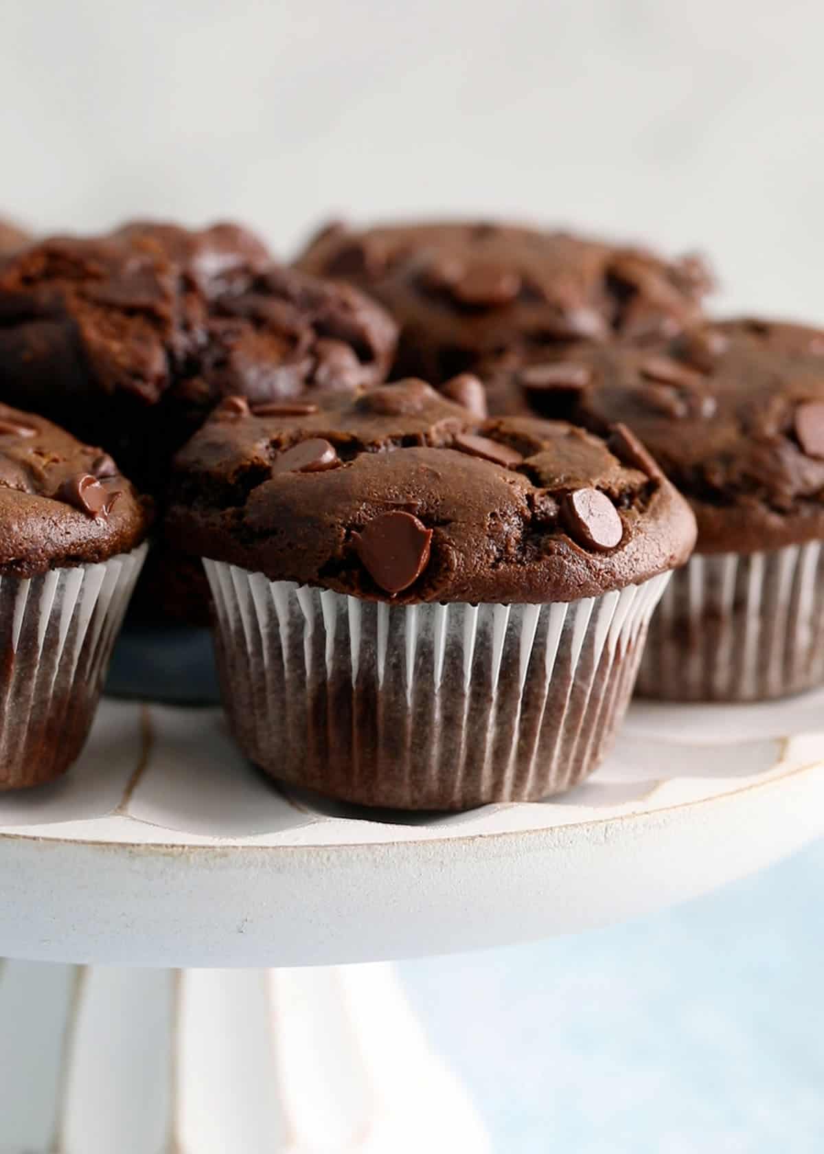 6 chocolate muffins placed on a white cake stand.