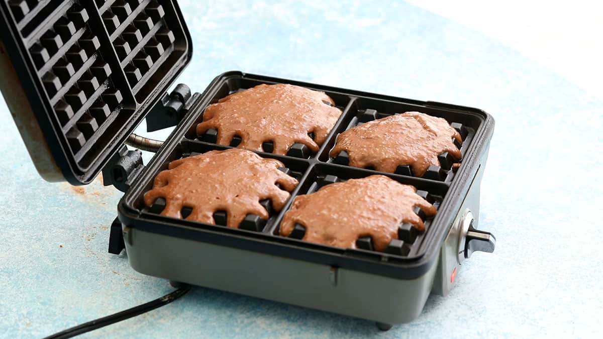 a waffle iron is filled with brown chocolate waffle batter.