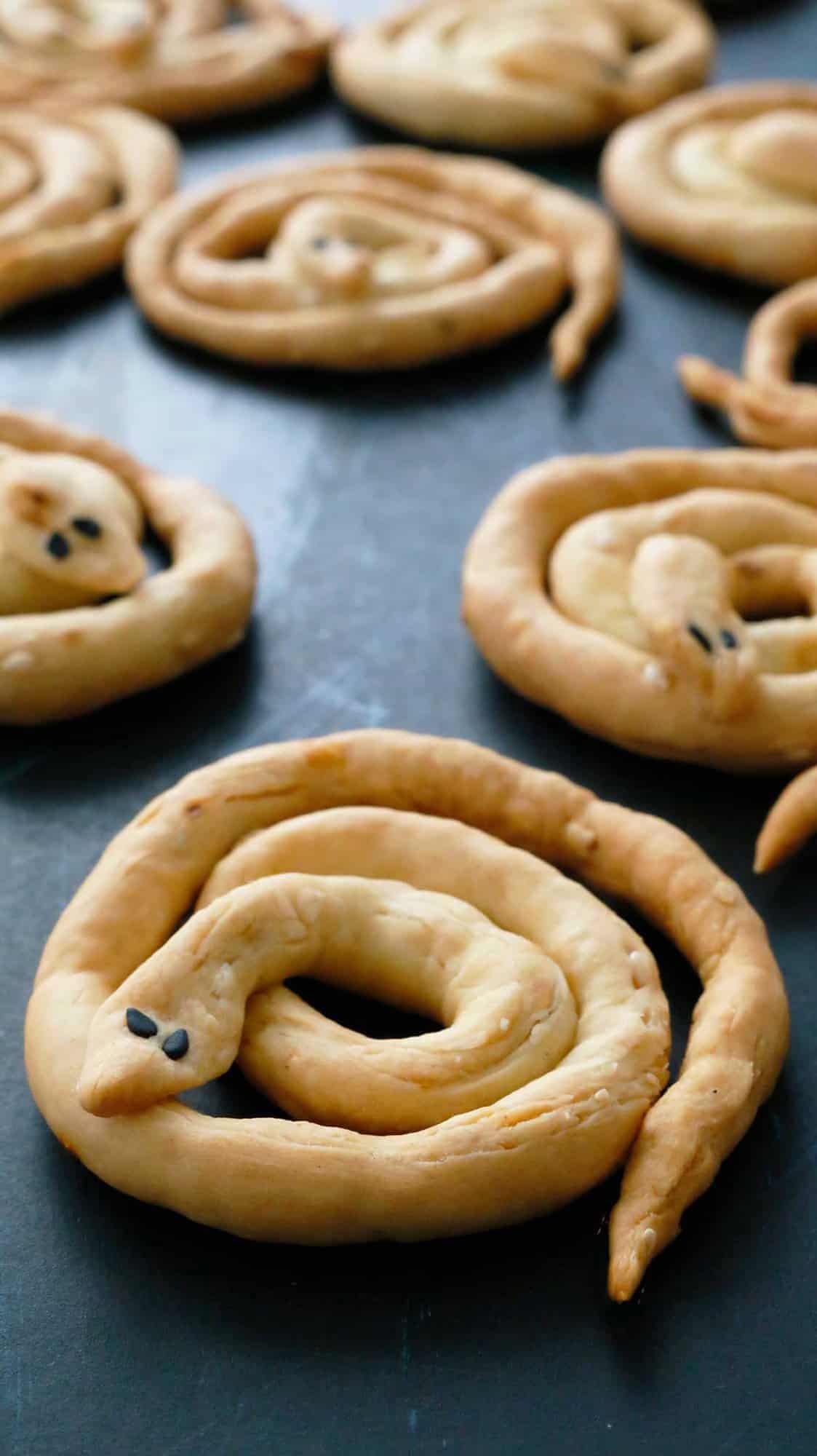 halloween breadsticks made in the form of snakes on a black board.