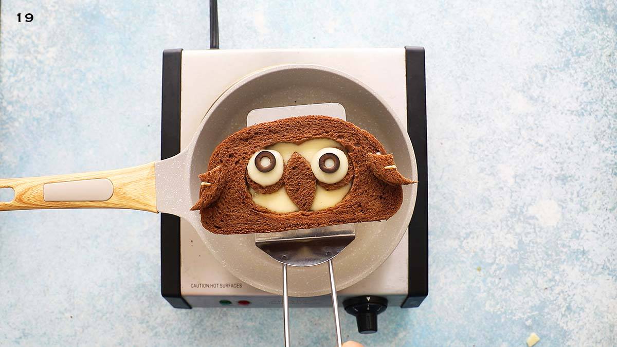 a flat spatula lifting a cooked halloween sandwich from a pan.