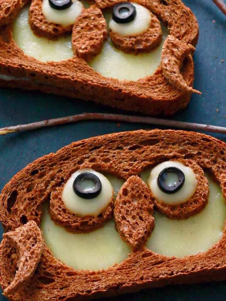two sandwiches in the shape of owls on a black board.