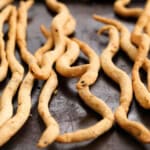 Snake shaped Halloween breadsticks on a black tray.