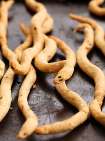 Snake shaped Halloween breadsticks on a black tray.