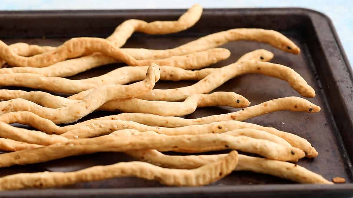 Snake shaped Halloween breadsticks on a black tray.