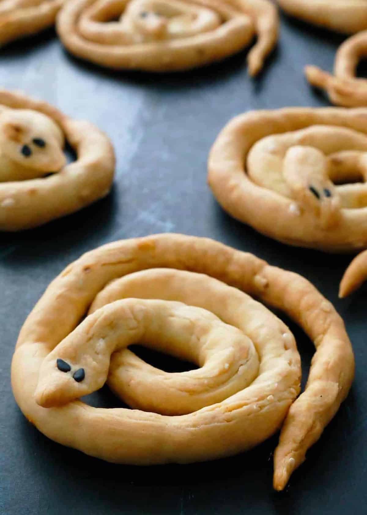 Snake shaped Halloween breadsticks on a black tray.
