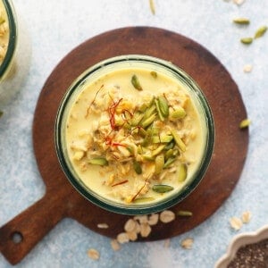 yellow overnight oats topped with green pistachios in a glass jar.