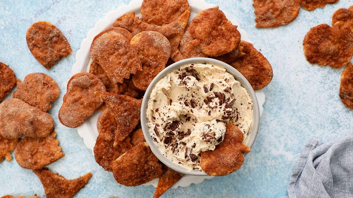 white cinnamon dip in a grey bowl with brown chips placed around it.