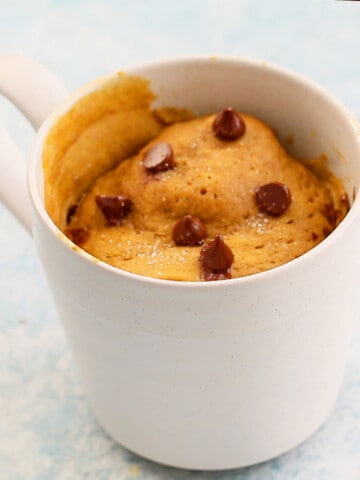 cooked pumpkin cake topped with chocolate chips in a white mug.