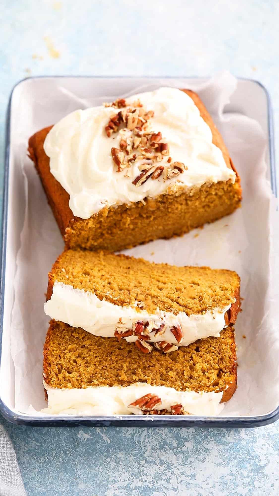 sliced pumpkin cake topped with chopped pecans on a white tray. 