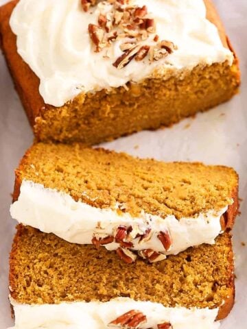 sliced pumpkin cake topped with chopped pecans on a white tray.