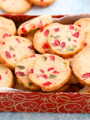 a red cookie box is filled with Christmas cookies.