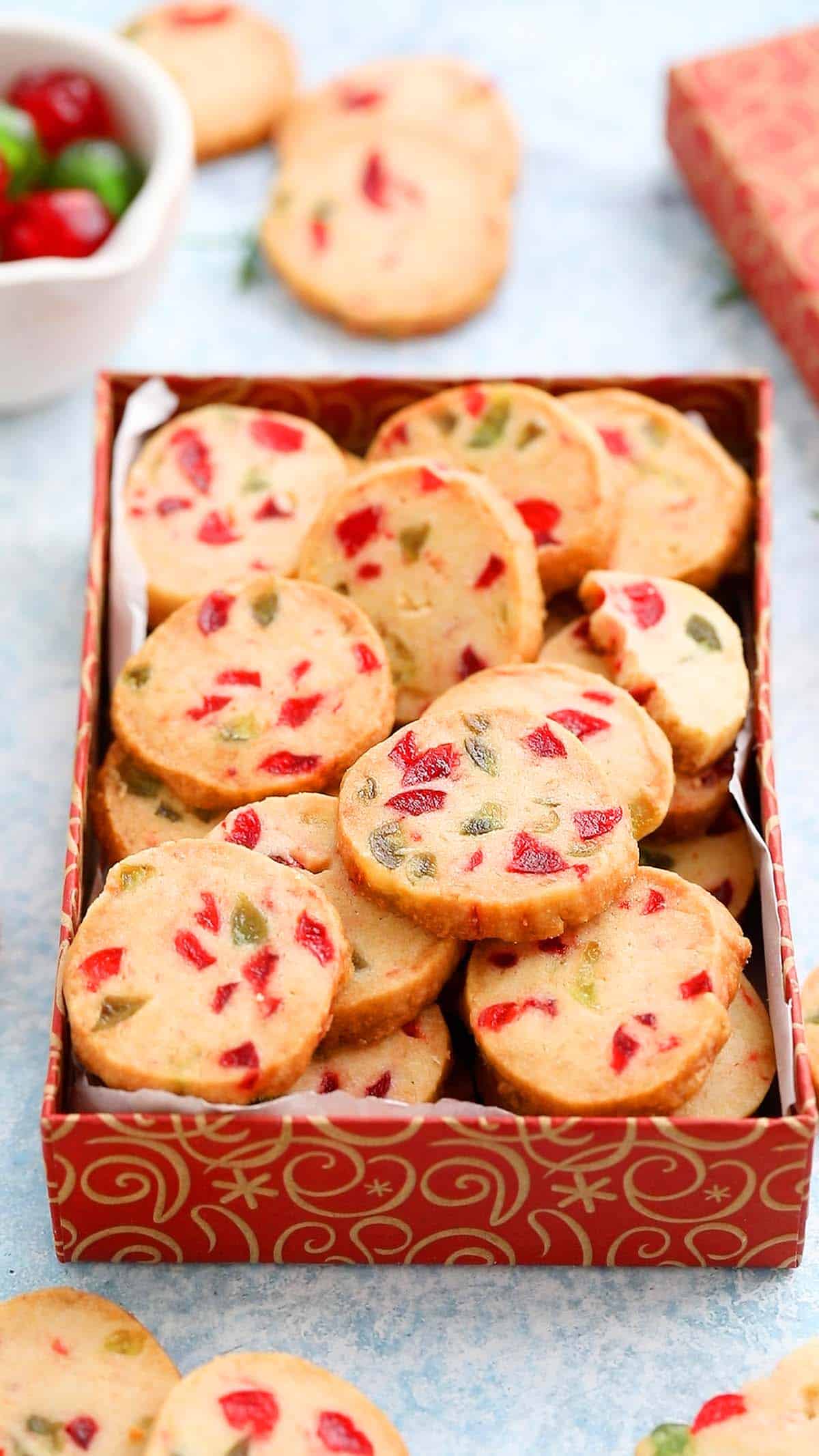 a red cookie box is filled with Christmas cookies.