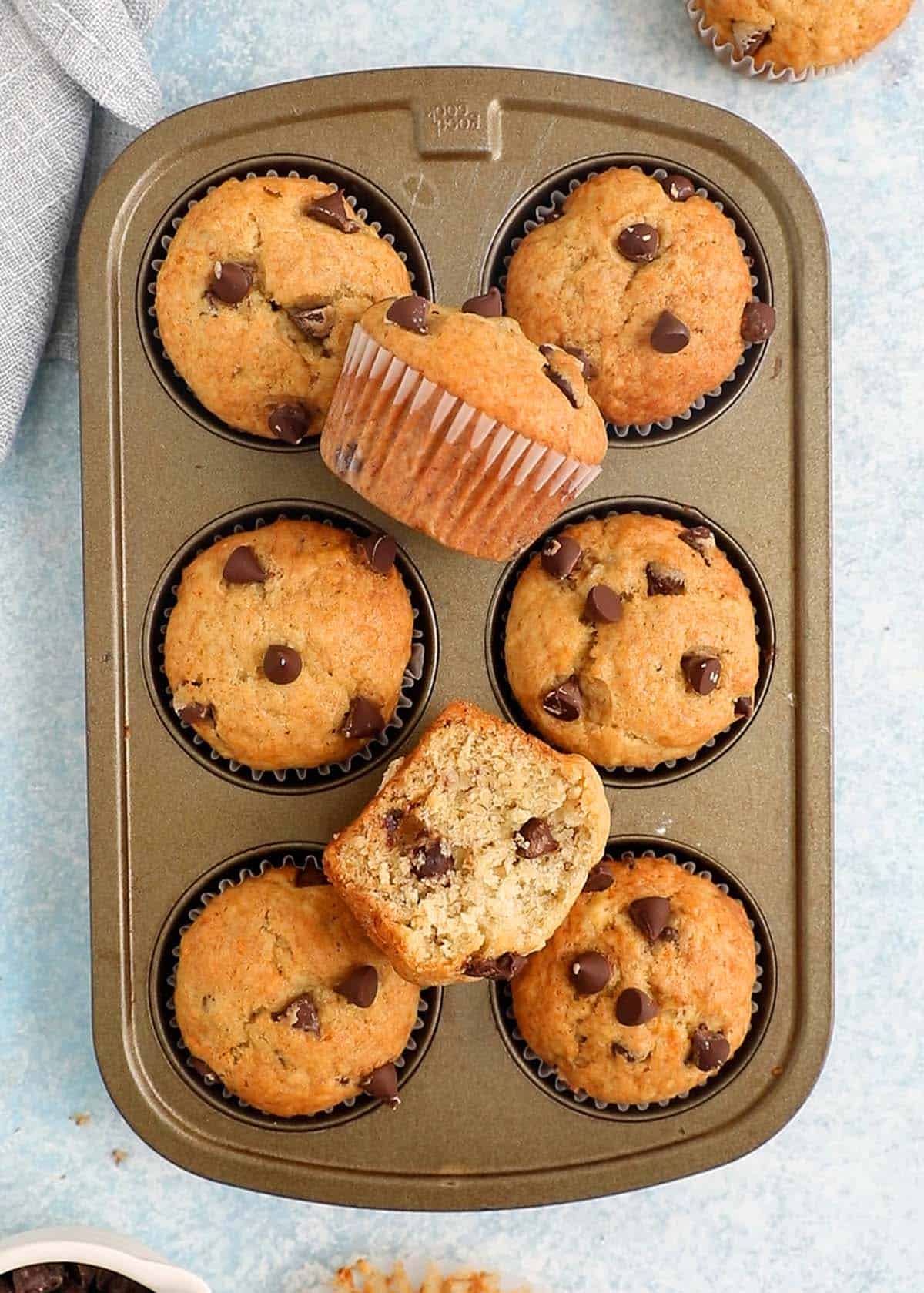6 baked banana chocolate chip muffins in a muffin pan.
