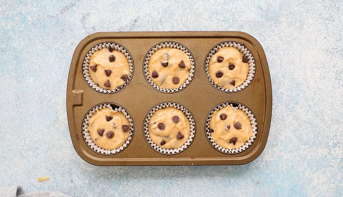 one 6 cup muffin pan with banana muffin batter.