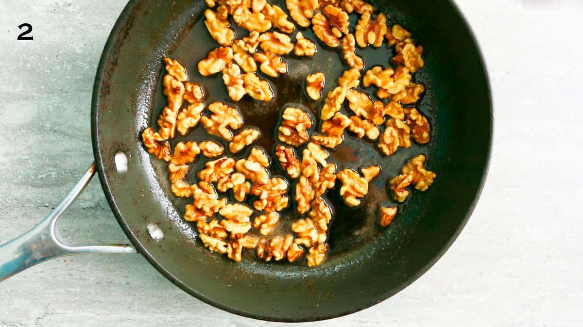 caramel walnuts cooking in a black skillet.