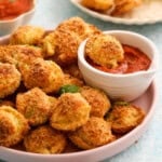 golden brown breaded tortellini in a pink plate along with red sauce.