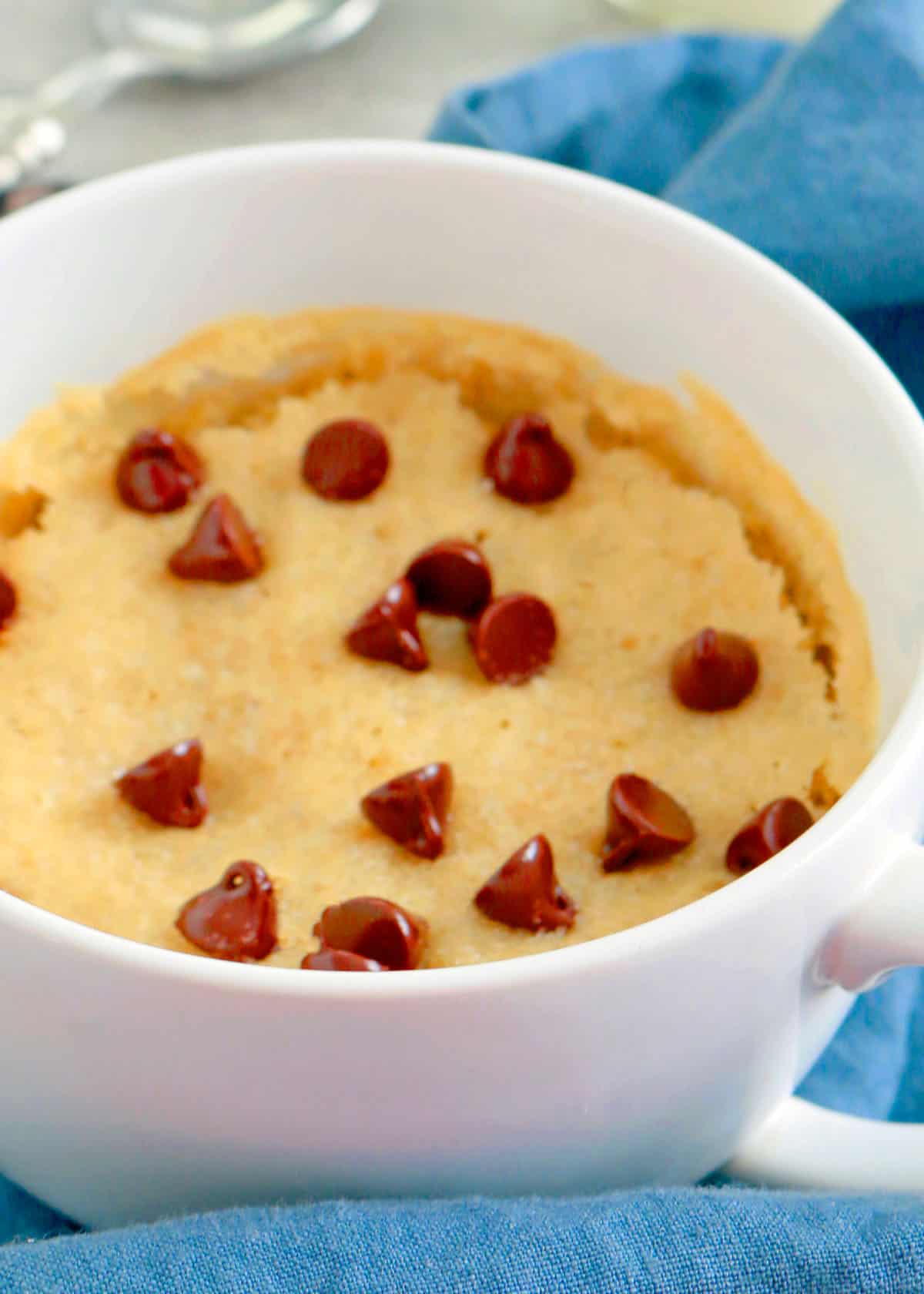 brown cake topped with chocolate chips in a white mug.