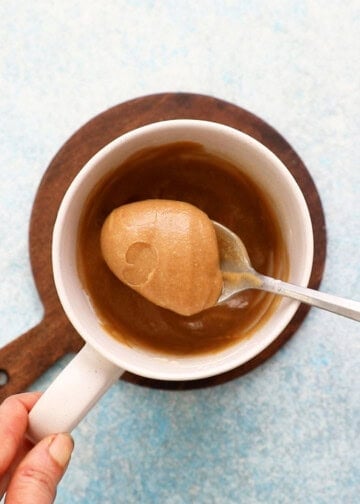 a spoonful of brown mug cake batter above a white mug.