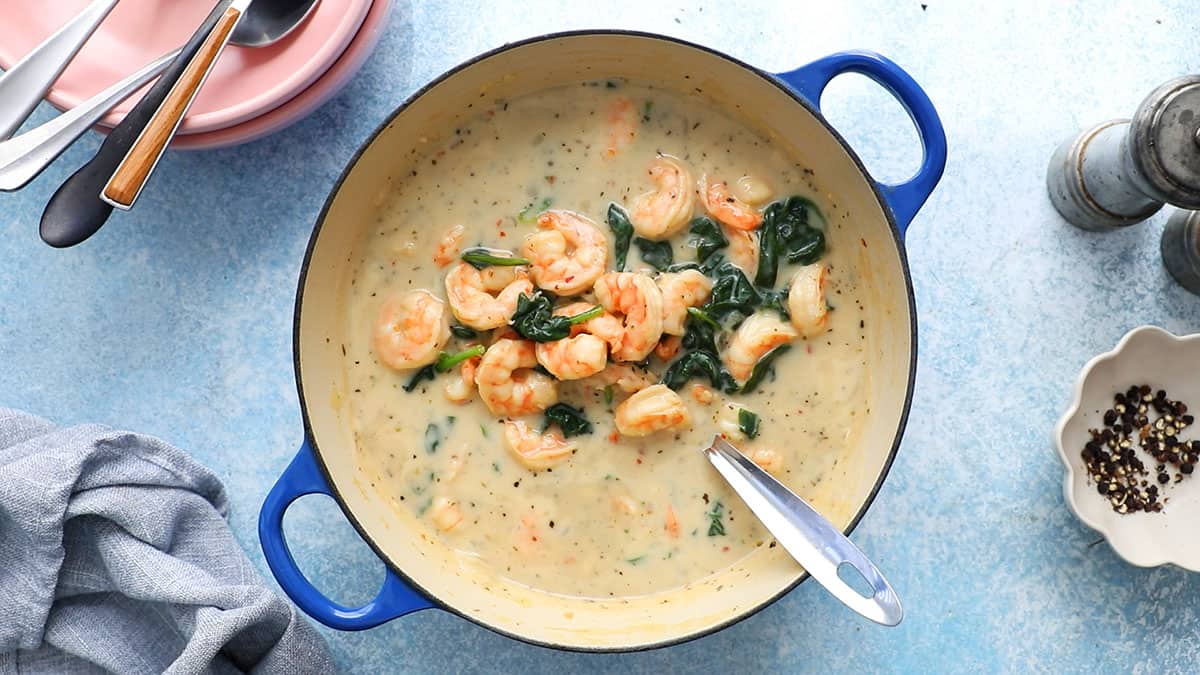 cooked spinach and shrimp soup in a white pot.