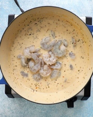 raw shrimp in a pot of creamy white soup.
