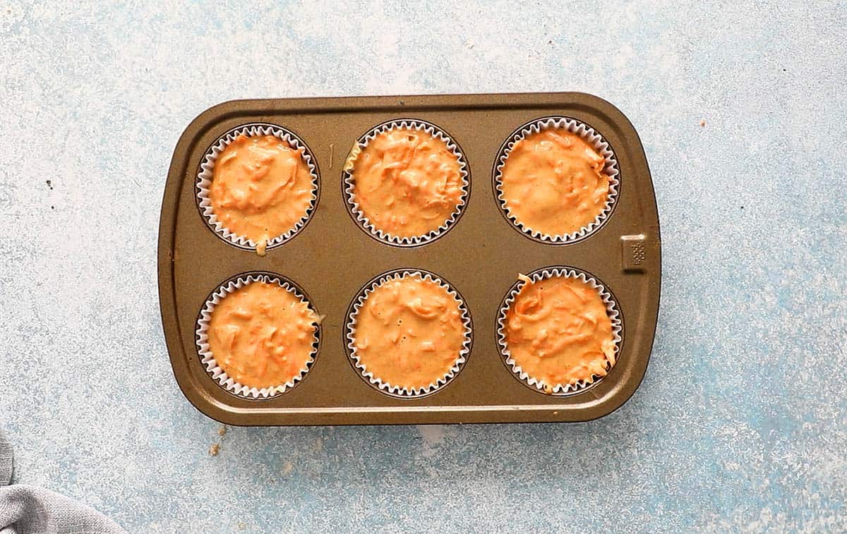 6 cup metal muffin pan filled with batter.