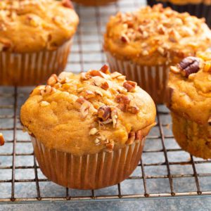 sweet potato muffins topped with pecans on a wire rack.