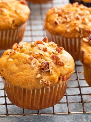 sweet potato muffins topped with pecans on a wire rack.