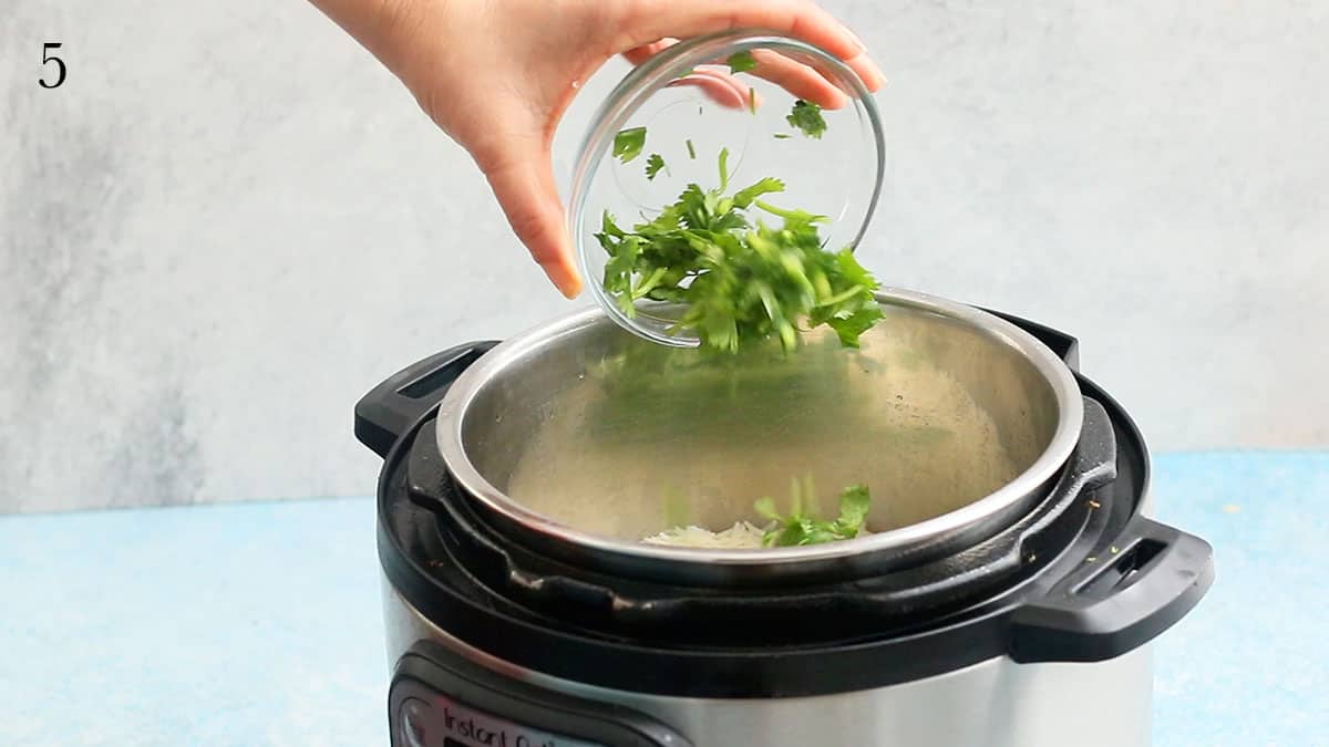 a hand adding cilantro into an instant pot.