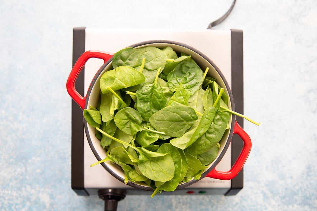 a red pot filled with fresh spinach leaves.