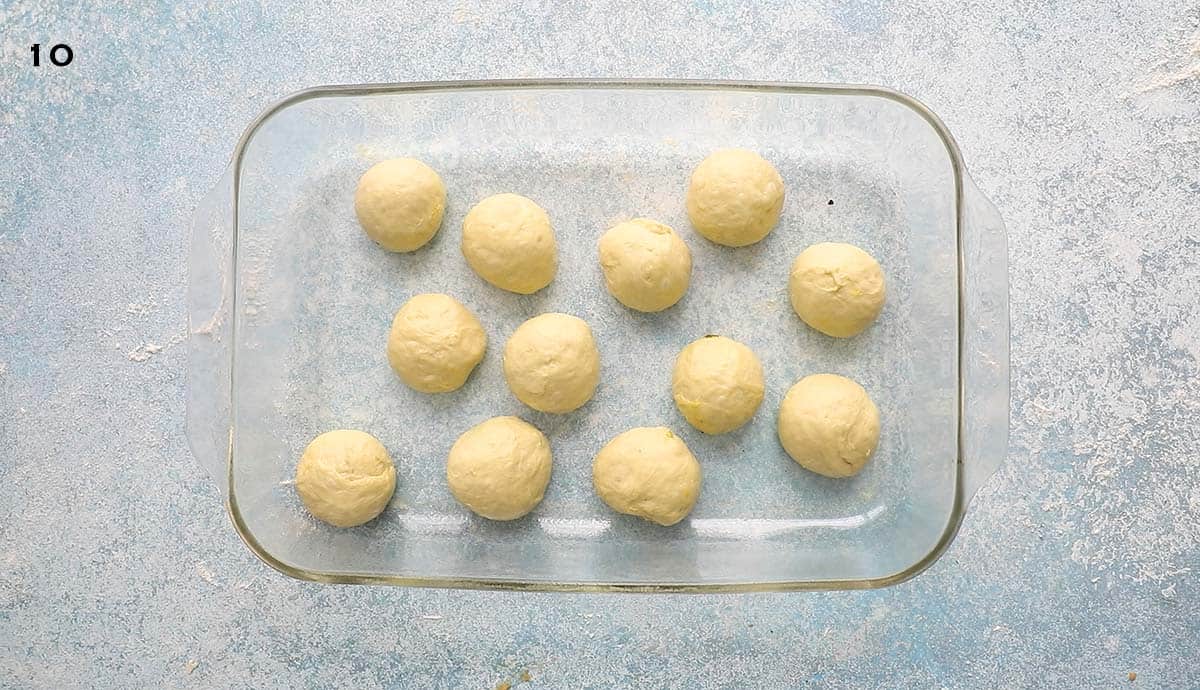 12 yeast dough balls placed in a rectangular glass dish.